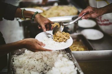 Yoksullara yemek veren dilencilerin elleri, hizmet sağlayıcılardan sadaka alıyor: yoksulluk ve gıda kıtlığı kavramı.