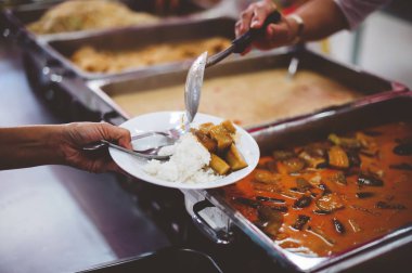 Gönüllüler tarafından yardım edilen dilencilerin elleri lezzetli yiyecekler sunuyordu: yoksulluk kavramı..
