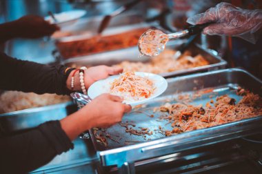 Gönüllülerin ellerinden yemek alan dilencilerin elleri.