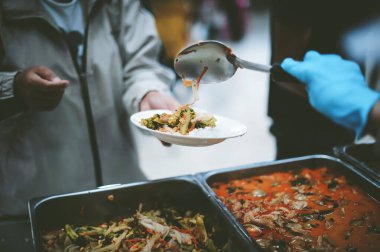 Tabak taşıyan yoksul insanlar gönüllülerden yiyecek yardımı alıyor: yardım kavramı