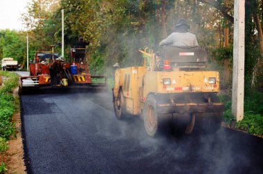 Asfalt kaldırımındaki ağır titreşimli paten sıkıştırıcısı yol onarımı için çalışıyor