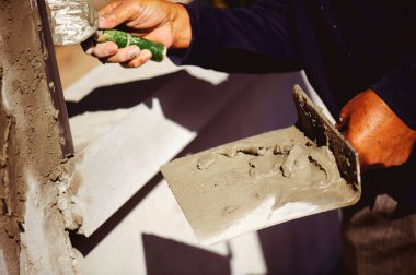 İşçiler beton sütunları güzel bir sırta süslemek için bir mala kullanıyorlar..