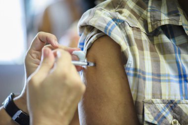 Koluna iğne batırılmış bir doktordan grip aşısı alıyorum..