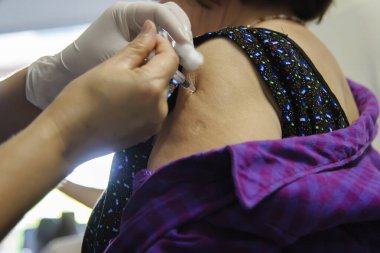 Aşı aşısı, doktor hasta koluna aşı enjekte ediyor.