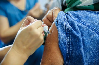 Aşı aşısı, doktor hasta koluna aşı enjekte ediyor.