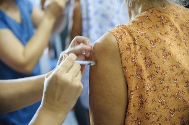 Aşı aşısı, doktor hasta koluna aşı enjekte ediyor.