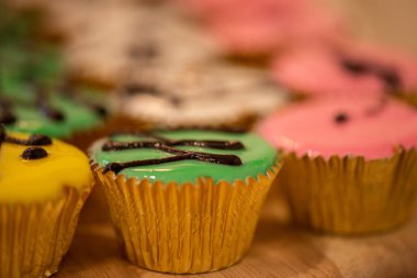 Kekler çeşitli renkler ve tatlar altın bardaklarda ahşap kesiminde.