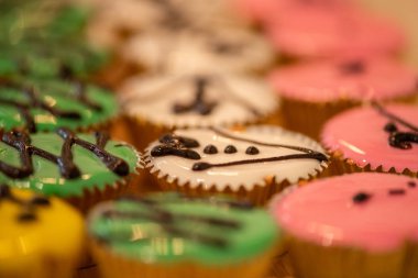 Kekler çeşitli renkler ve tatlar altın bardaklarda ahşap kesiminde.