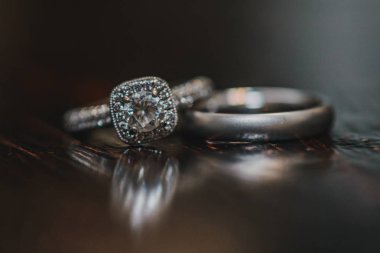 Tahta yansıtıcı yüzeyinde elmasları olan gümüş alyanslar.