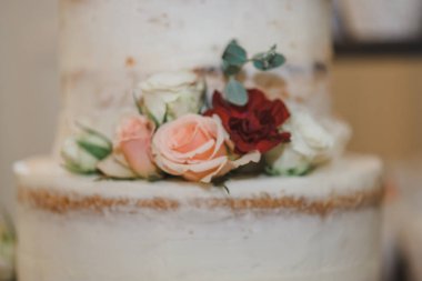 Beyaz üç katmanlı çıplak düğün pastası pembe, kırmızı ve beyaz gül