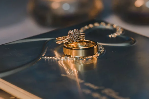 反射テーブルの上にダイヤモンドとゴールドハートの結婚指輪 — ストック写真
