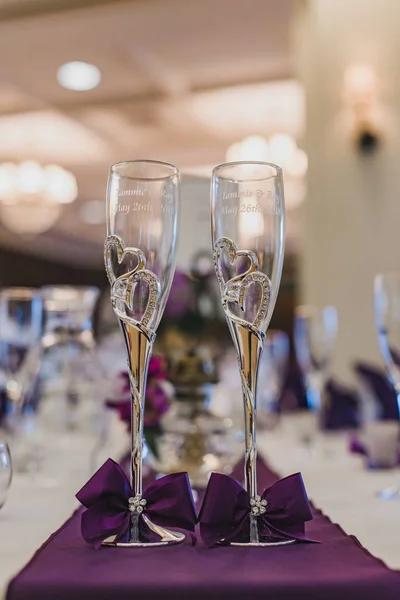 Two wine glasses with gold hearts on dinner table with purple runner