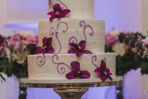 White three tier wedding cake with purple flowers decor