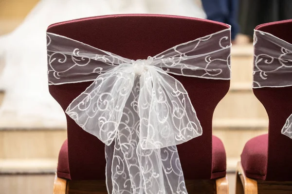 Costas de cadeiras vermelhas da igreja elegante com arcos de renda e fita — Fotografia de Stock