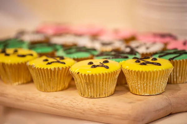 Cupcakes various colors and flavors in gold cups on wood cutting — Stock Photo, Image