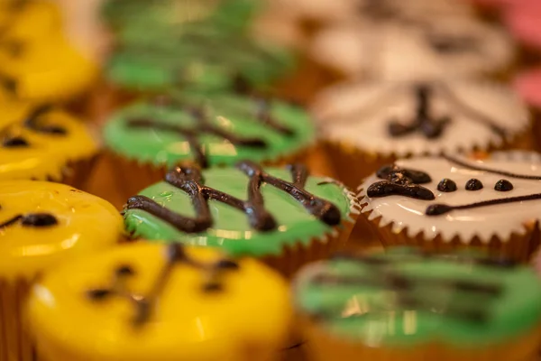 Cupcakes várias cores e sabores em copos de ouro no corte de madeira — Fotografia de Stock