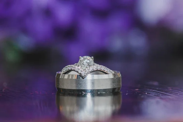 Anéis de casamento de prata com reflexão e fundo bokeh roxo — Fotografia de Stock