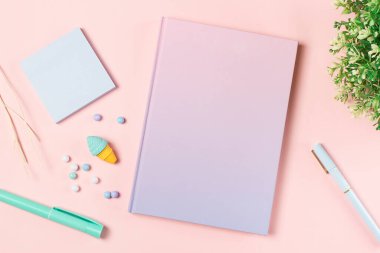 Pembe pastel arka planda çalışma masasının üzerine yaslanmış kırtasiye malzemesi