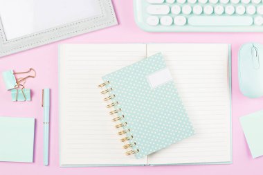 Pembe pastel arka planda çalışma masasının üzerine yaslanmış kırtasiye malzemesi