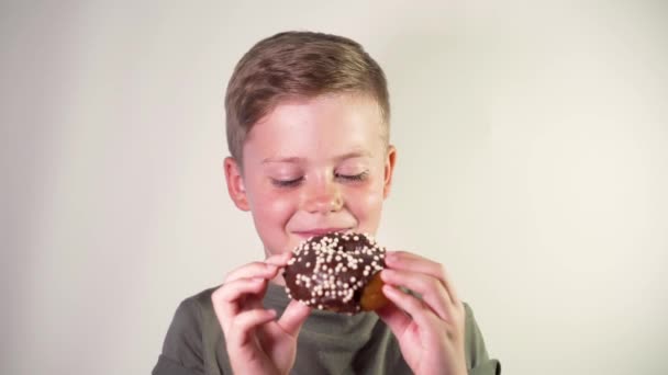 Симпатичный маленький мальчик ест вкусный пончик — стоковое видео