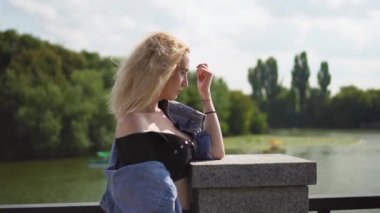 Beautiful Caucasian Blonde Girl Near Riverside Fountain on a Sunny Day