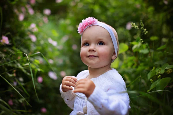 喜びに満ちた小さな女の子は野生のバラの花の近くに立っています — ストック写真