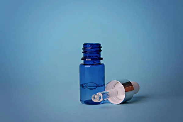 Cosmetisch serum. Druppelaar met een druppel serum op een blauwe achtergrond. — Stockfoto