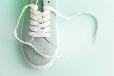 Açık mavi arka planda beyaz bağcıklı mavi spor ayakkabılar..