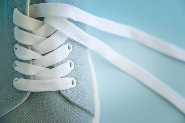 Голубые кроссовки с белыми шнурками на голубом фоне. — стоковое фото