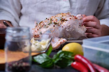 Bir adam biber, limon ve otlar karışımı ile tavuk ovuşturuyor. Fırında tavuk pişirme işlemi. Masada yemek pişirmek için gerekli olan ürünler vardır. Çerçeve içinde aşçı nın elleri.