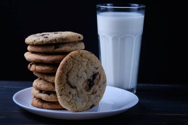 Amerikan çikolata kurabiyeleri. Bir kule şeklinde çerez yığını. Kurabiye ve bir bardak süt.