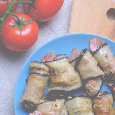 Sarımsak ve baharatlar ile karışık et ve ekmek kırıntıları ile patlıcan rulo. Peynir ve baharatlar ile süslenmiş beyaz seramik formunda rulo. Koyu ahşap arka planda rulo