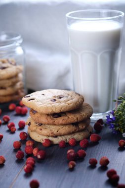 Amerikan çikolata kurabiyeleri. Bir olabilir çerez. Bir kule şeklinde çerez yığını. Çerezler, bir bardak süt, çilek, çiçekler ve bir nevresim havlusu. Kırsal hala yaşam.