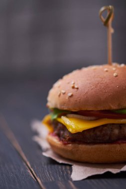 Klasik Amerikan cheeseburger. Koyu ahşap arka planda cheeseburger.