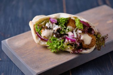 Marul, mavi soğan ve tahin sosu ile pide içinde falafel. Vejetaryen Shawarma. Hızlı yemek. Genel form