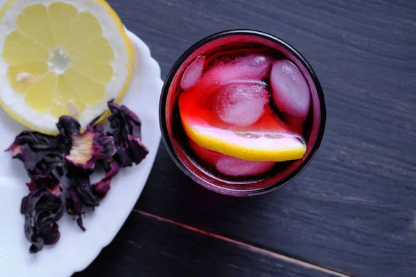 Limon, bal ve buz ile Hibiscus çayı, beyaz bardakta cam ve yeşil çay. Koyu ahşap arka planda çay