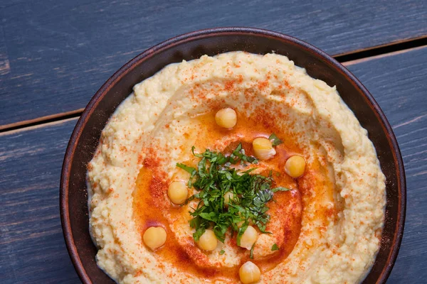 Classic hummus with hot peppers in a clay plate. National, vegetarian dish