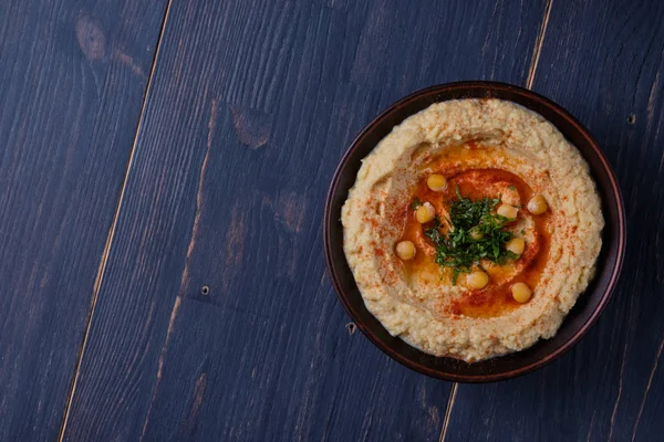 Classic hummus with hot peppers in a clay plate. National, vegetarian dish
