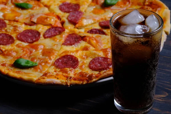 Pepperoni and Margarita. Two pizzas together and a cola on a wooden table