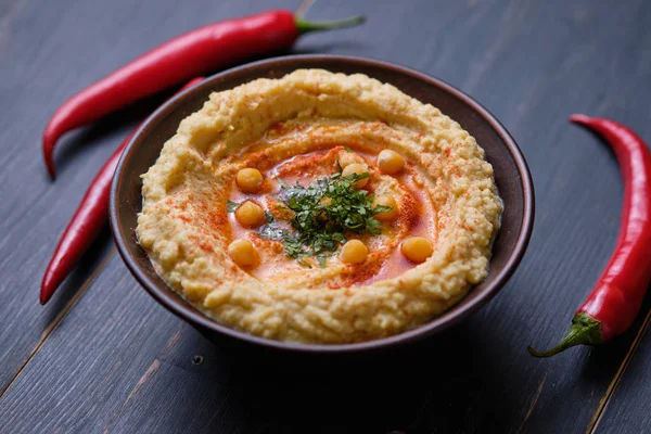 Classic hummus with hot peppers in a clay plate. National, vegetarian dish