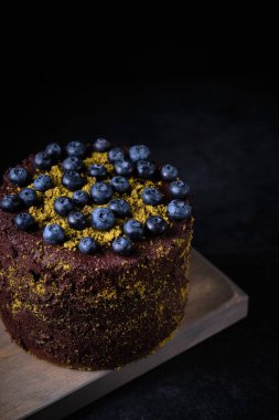 Böğürtlenli çikolatalı pasta, yer fıstığı ve ahşap bir tahtanın üzerinde taze böğürtlenlerle süslenmiş..