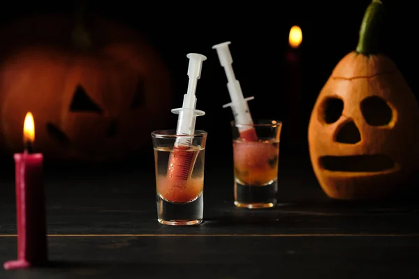 Halloween bloody mary cocktail and two sinister jack lanterns on a dark wooden table.