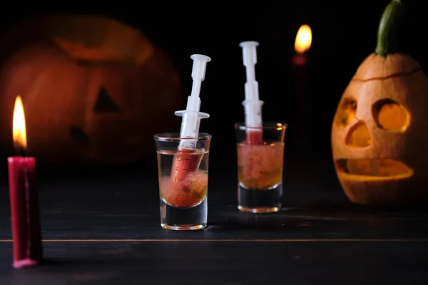 Halloween bloody mary cocktail and two sinister jack lanterns on a dark wooden table.