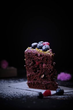 Tahta bir masada kiraz ve yaban mersinli bir dilim çikolatalı pasta. Lezzetli bir tatlı. Taze ve güzel bir pasta..