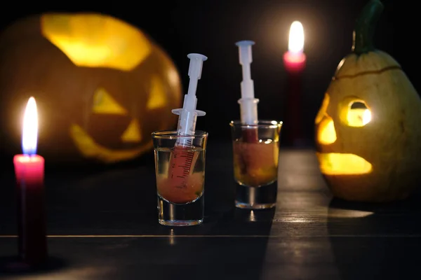 Halloween bloody mary cocktail and two sinister jack lanterns on a dark wooden table.