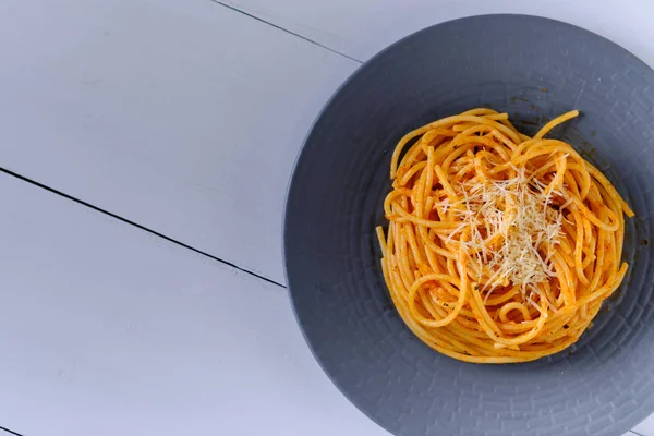 Domates soslu ve parmesanlı spagetti. Beyaz ahşap bir masada makarna. Öğle yemeğinde İtalyan yemeği..