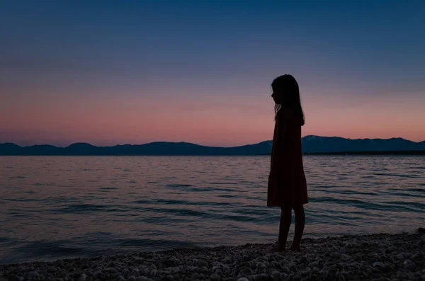 Ufukta bakan bir plajda duran genç bir kızın silueti