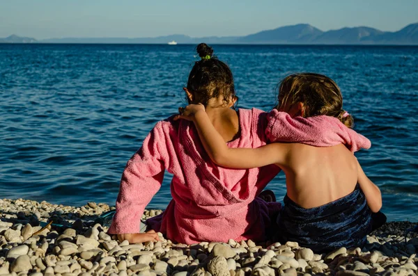 Сестры сидят у моря после купания, обнимаются — стоковое фото