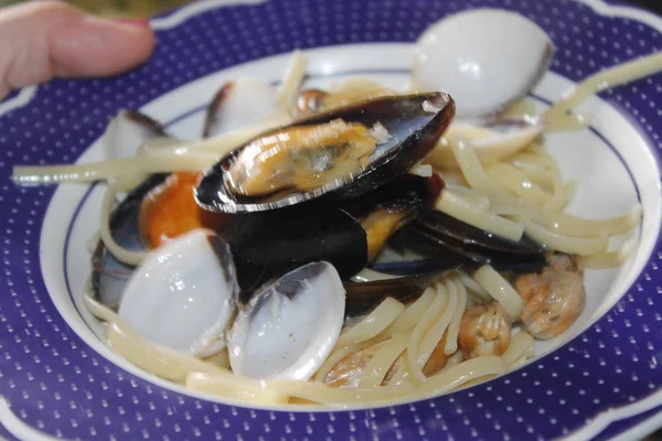 a plate with pasta and seafood with clams, prawns, shrimps, mussels