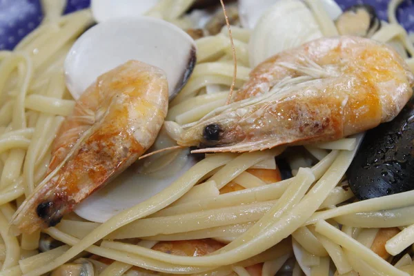 a plate with pasta and seafood with clams, prawns, shrimps, mussels